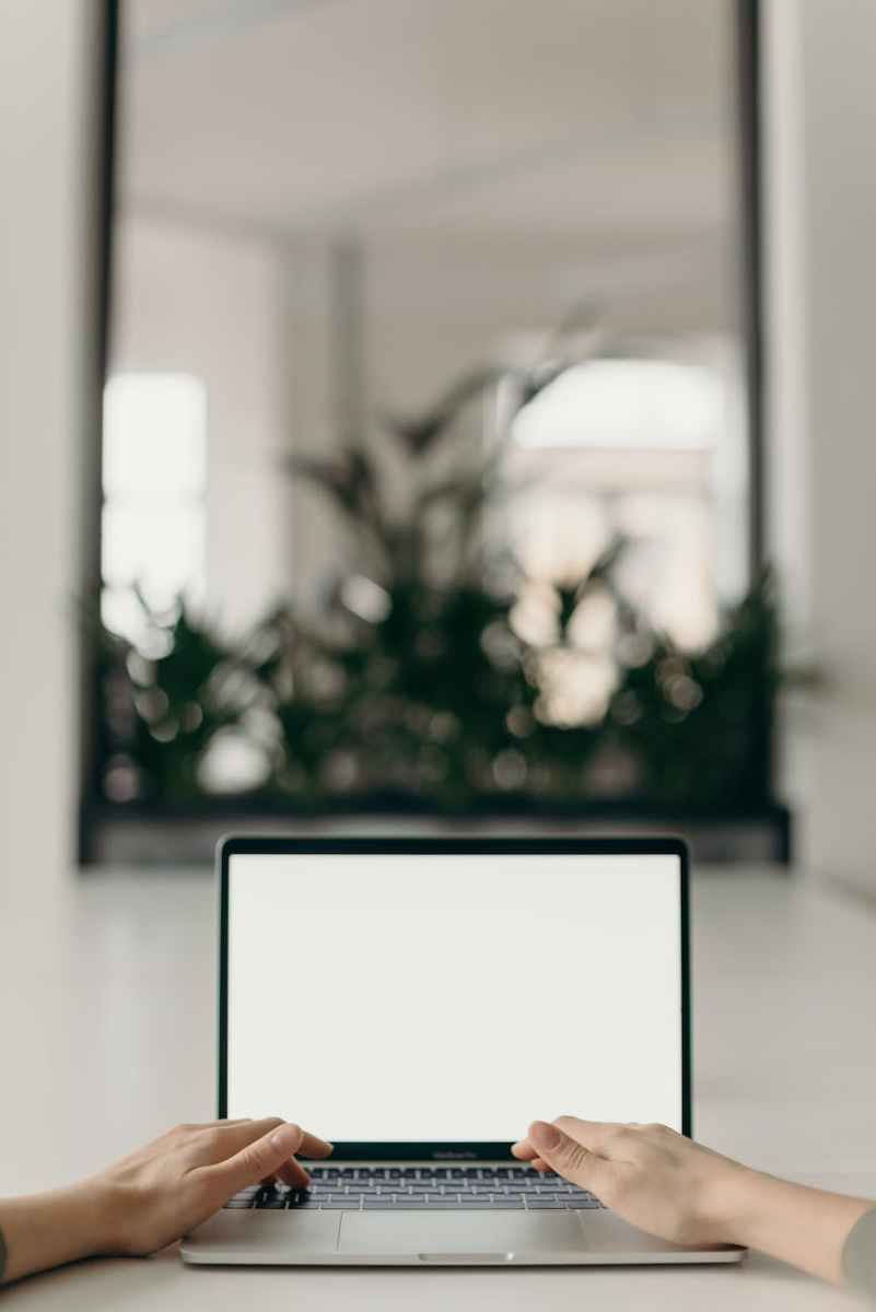 Two hands positioned near a laptop with a blank screen